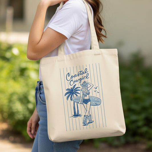 Canvas tote bag with "Coastal Cowgirl" text and illustration of a cowgirl with surfboard.