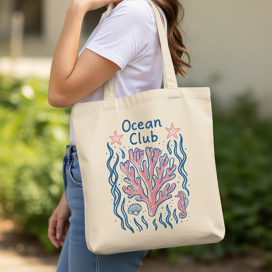 Beige tote bag with a pink coral, seahorse, and starfish illustration.