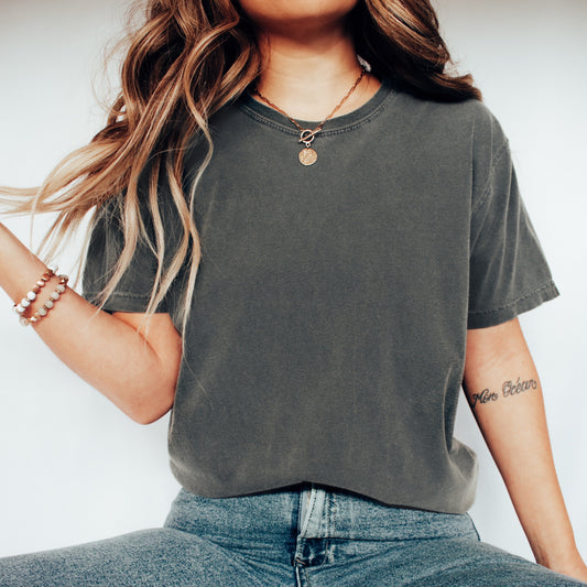 Person wearing a gray t-shirt and blue jeans with white sneakers on a plain background