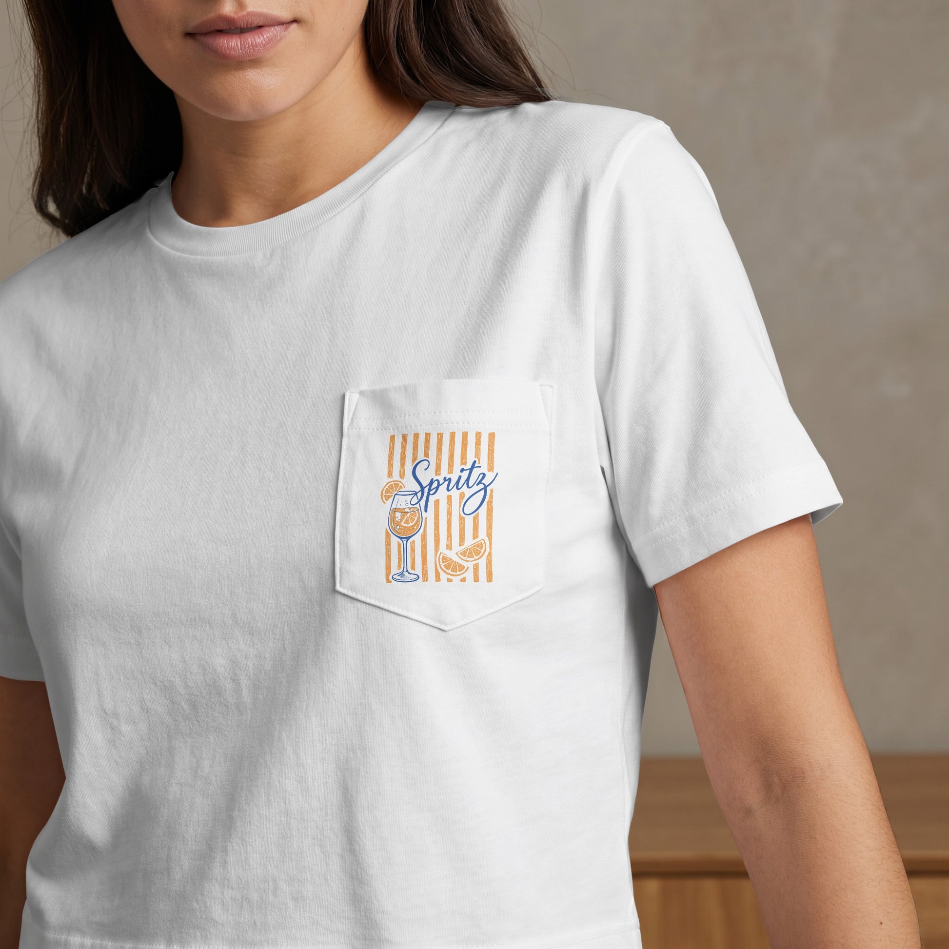 White t-shirt with a pocket design featuring an orange slice, a glass, and the word "Spritz".